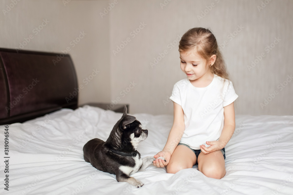little blonde girl playing with a black dog