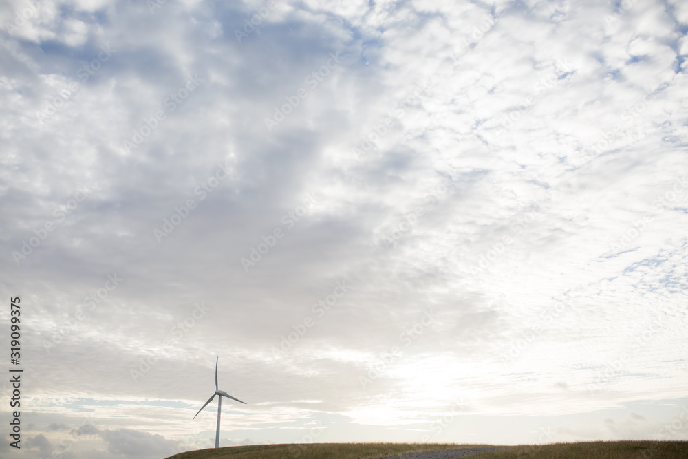 Fototapeta premium a wind turbine on a hill with setting sun behind
