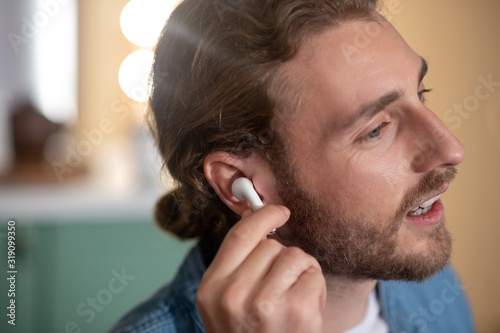 Handsome long-haired man wearing white wireless earphones