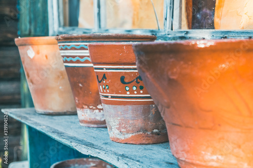 Vintage clay pots with ornamental pattern standing in rows on shelves