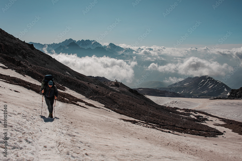 Man walking on the snowy path looking down climbing on the mountain Man walking on the snowy path looking down climbing on the mountain