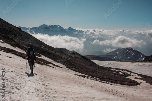 Man walking on the snowy path looking down climbing on the mountain