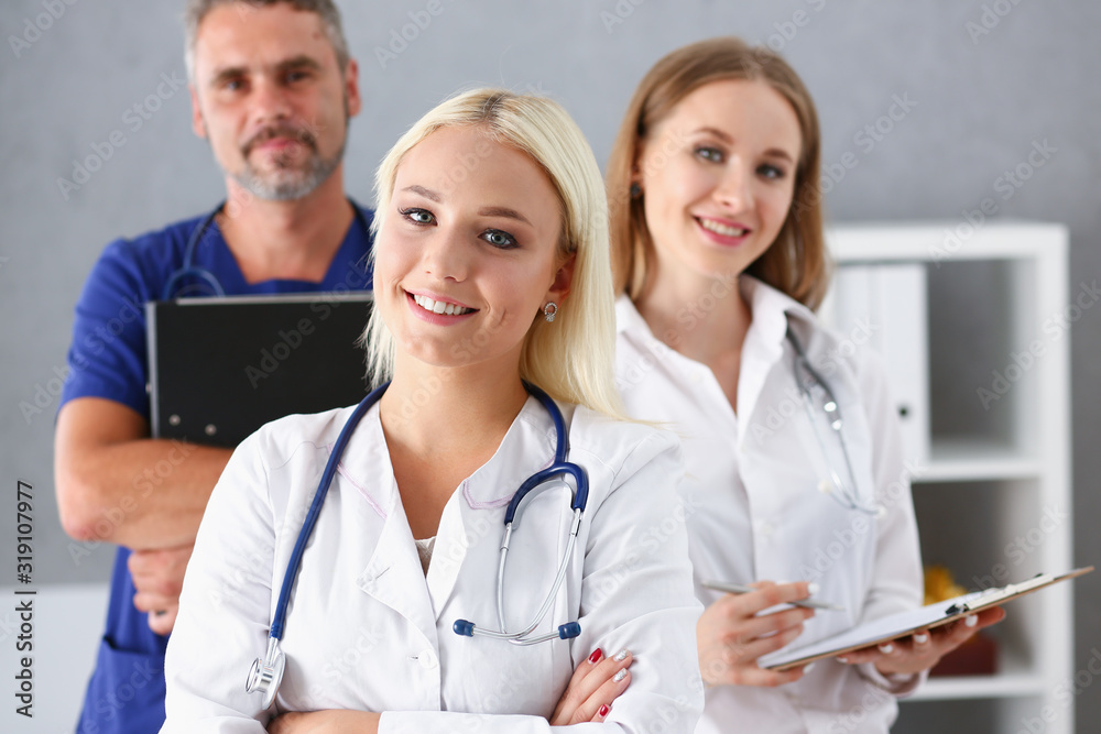 Beautiful smiling female doctor stand in office portrait. Physical and patient disease prevention exam er ward round 911 prescribe remedy healthy lifestyle consultant nurse profession concept Beautiful smiling female doctor stand in office portrait. Physical and patient disease prevention exam er ward round 911 prescribe remedy healthy lifestyle consultant nurse profession concept