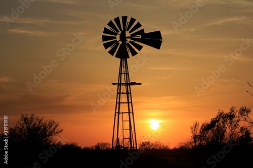 silhouette of windmill at sunset in Kansas with clouds.