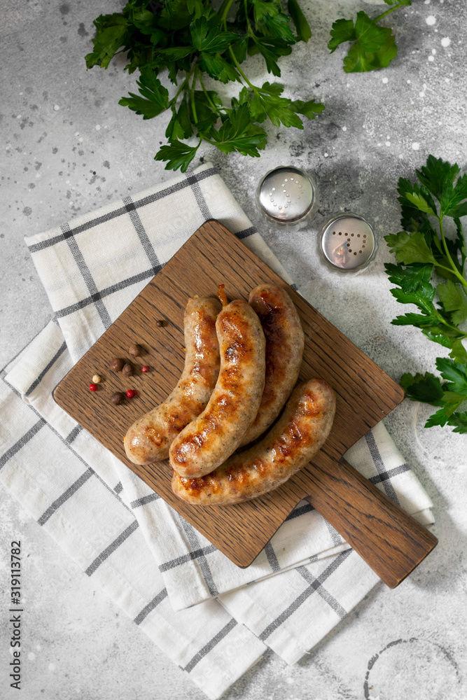 Grilled sausages on a wooden Board on a light gray kitchen table. View top