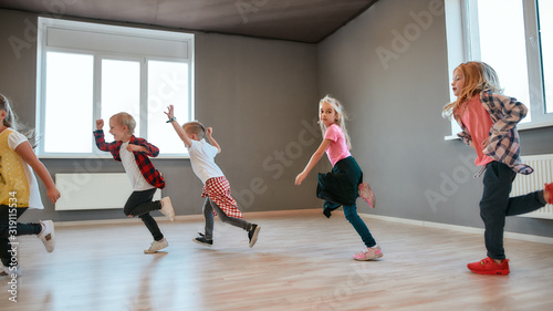 Full of energy. Little and happy boys and girls running in the dance studio. Warming up before dance class
