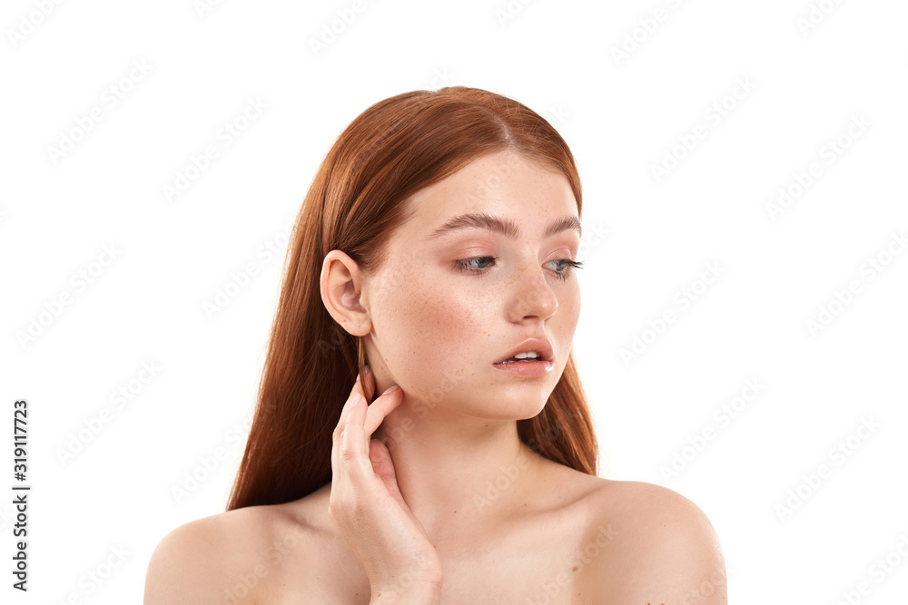 Perfect skin. Close up portrait of a young and beautiful red-haired girl with freckles on face looking away while standing against white background Perfect skin. Close up portrait of a young and beautiful red-haired girl with freckles on face looking away while standing against white background
