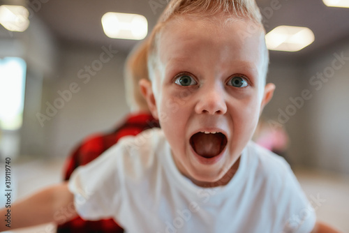 Going crazy. Portrait of funny little boy in white t-shirt looking at camera and screaming while having a choreography class in the dance studio