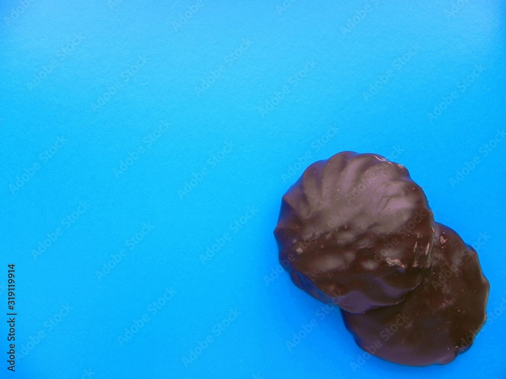 Marshmallows in chocolate on a blue background with space for text. Marshmallows in chocolate on a blue background with space for text.