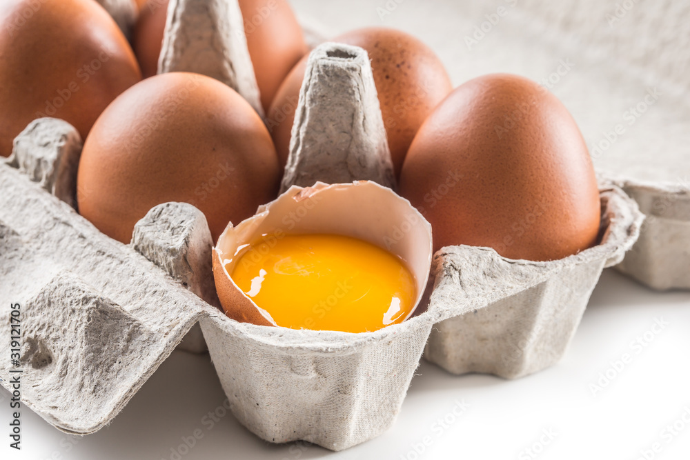 Fresh chicken eggs in pater tray with broken egg Fresh chicken eggs in pater tray with broken egg