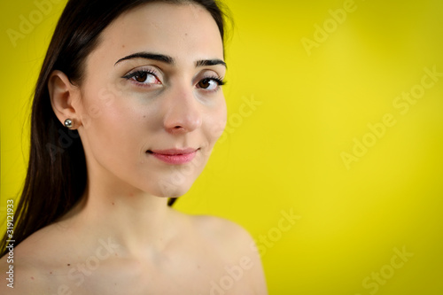 Versatile beauty concept of a cute smiling girl on a yellow background. Close-up Portrait of a pretty young brunette woman with excellent make-up.