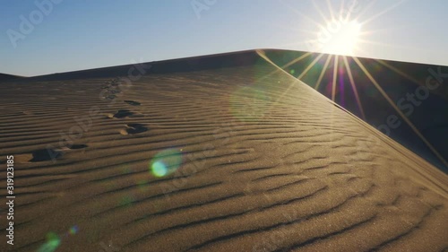 sand dunes at sunrise, walking along the sand dune in slow motion, bright sun shining in desert, dry hot scene photo