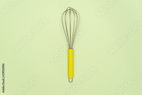 Clean new steel whisk isolated on white background. Cooking egg beater mixer whisker with wooden handle.