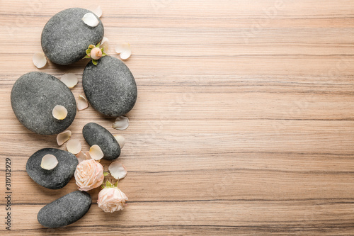 Stones and rose flowers on wooden background, top view with space for text. Zen lifestyle