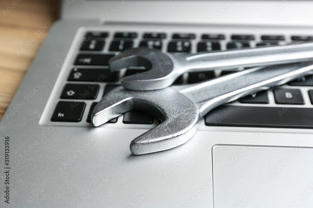 Fototapeta premium Laptop and spanners on table, closeup. Concept of technical support