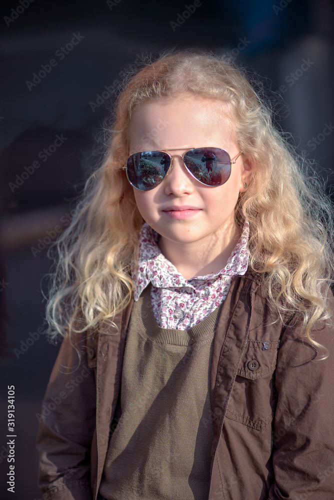 curly-haired blonde girl against the background of a brick wall and a glass window curly-haired blonde girl against the background of a brick wall and a glass window