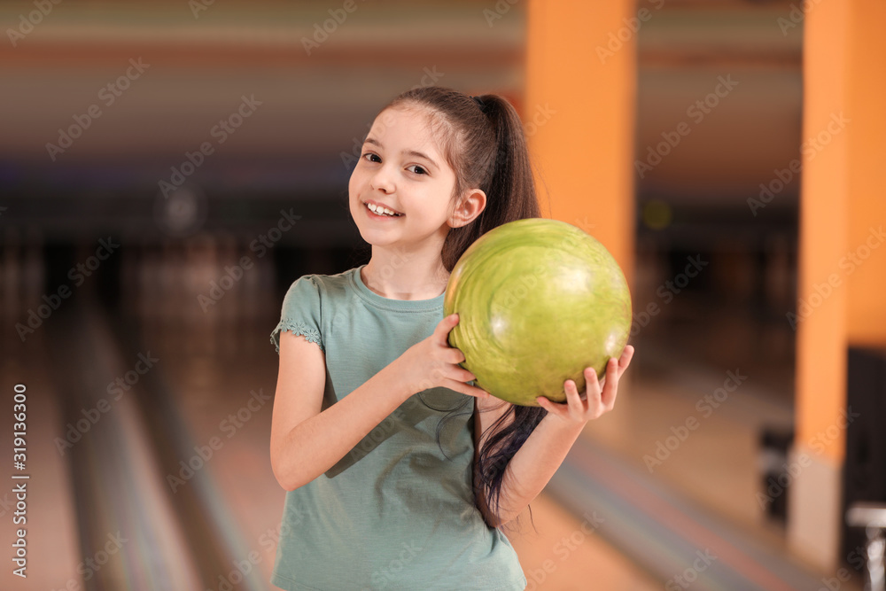 Fototapeta premium Little girl with ball in bowling club