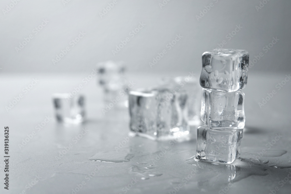 Crystal clear ice cubes with water drops on grey table. Space for text
