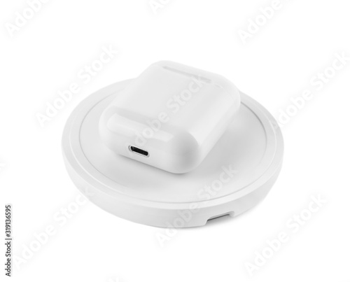 Earphones charging with wireless pad isolated on white