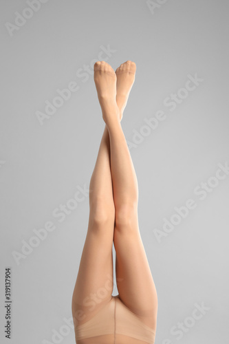 Woman wearing tights on light grey background, closeup of legs