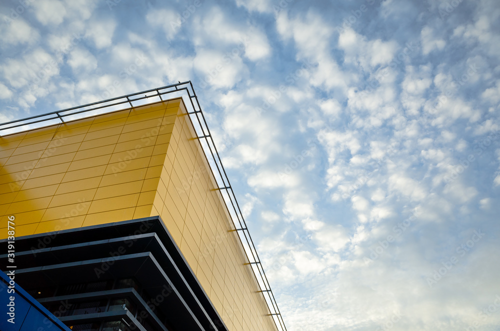 The yellow building stands out with the cloud sky in background in evening light. The yellow building stands out with the cloud sky in background in evening light.