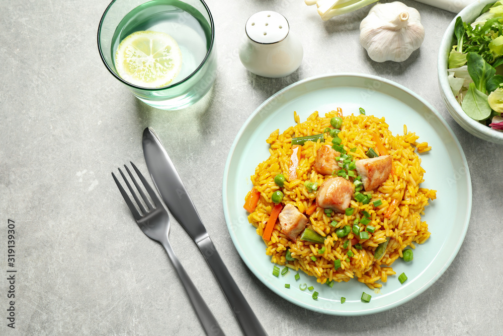 Delicious rice pilaf with vegetables and chicken served on light grey table, flat lay
