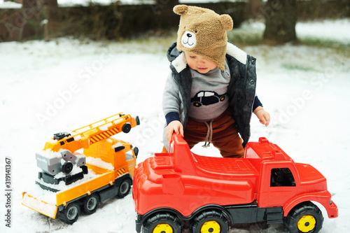 Baby boy and toy car in winter
