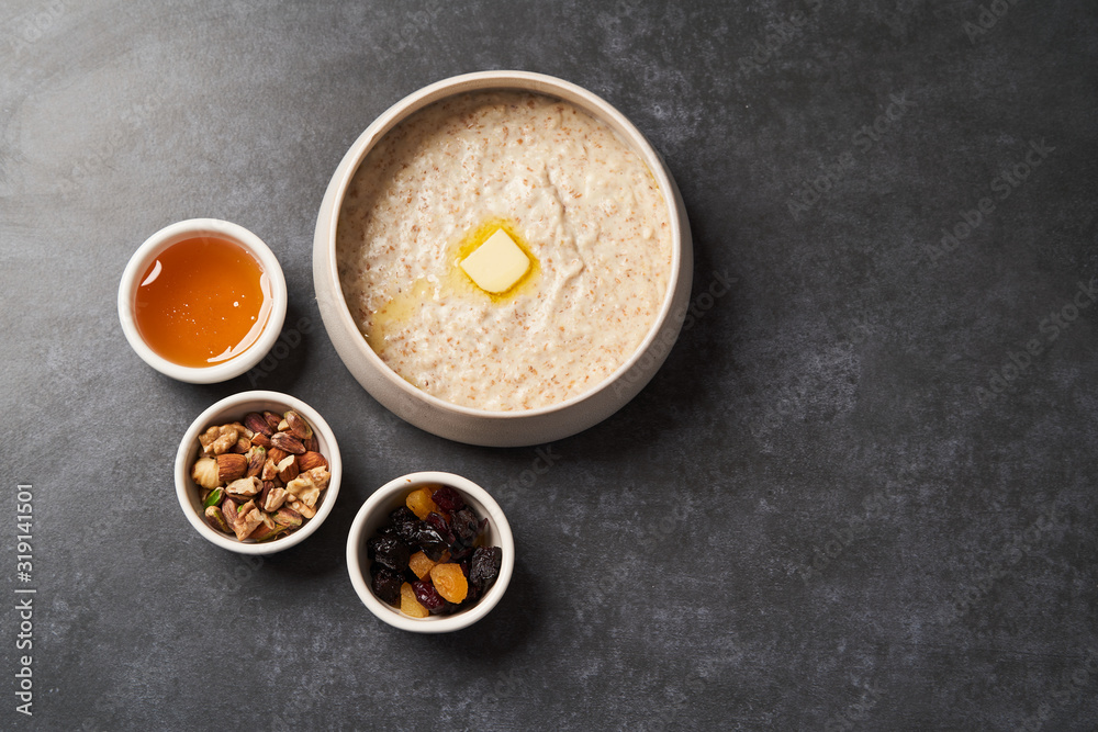 Oatmeal porridge with raisins, honey and nuts in a bowl Oatmeal porridge with raisins, honey and nuts in a bowl