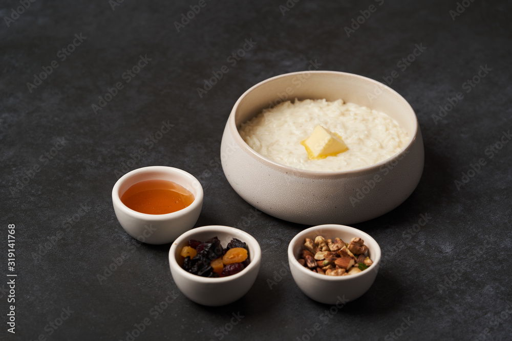 Rice porridge with milk, raisins, honey and nuts in a bowl. Rice porridge with milk, raisins, honey and nuts in a bowl.