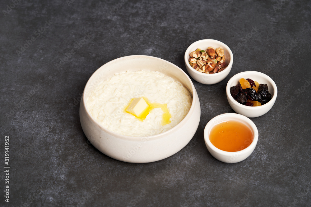 Rice porridge with milk, raisins, honey and nuts in a bowl. Rice porridge with milk, raisins, honey and nuts in a bowl.