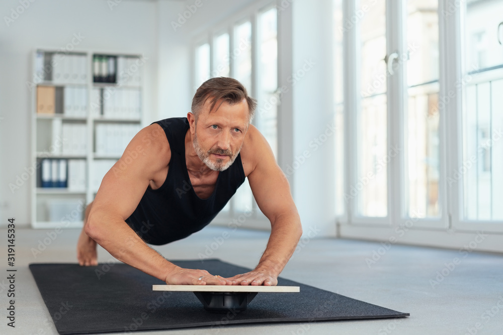 Middle-aged man exercising plank on balance board Stock Photo | Adobe Stock