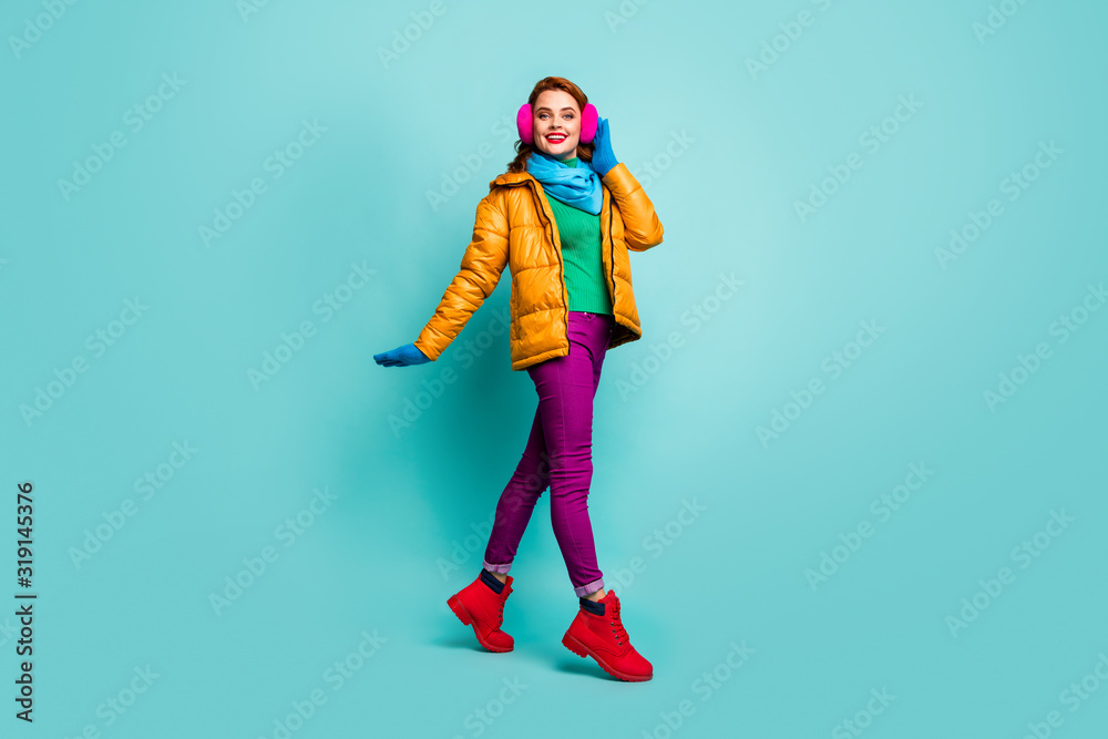 Full body photo of content candid woman enjoy winter autumn weekend go walk touch ear warmers wear pink red bright boots isolated over teal color background