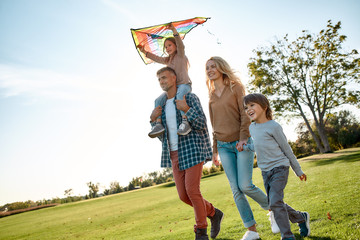 Children learn to smile from their parents. Happy family playing a kite. Outdoor family weekend