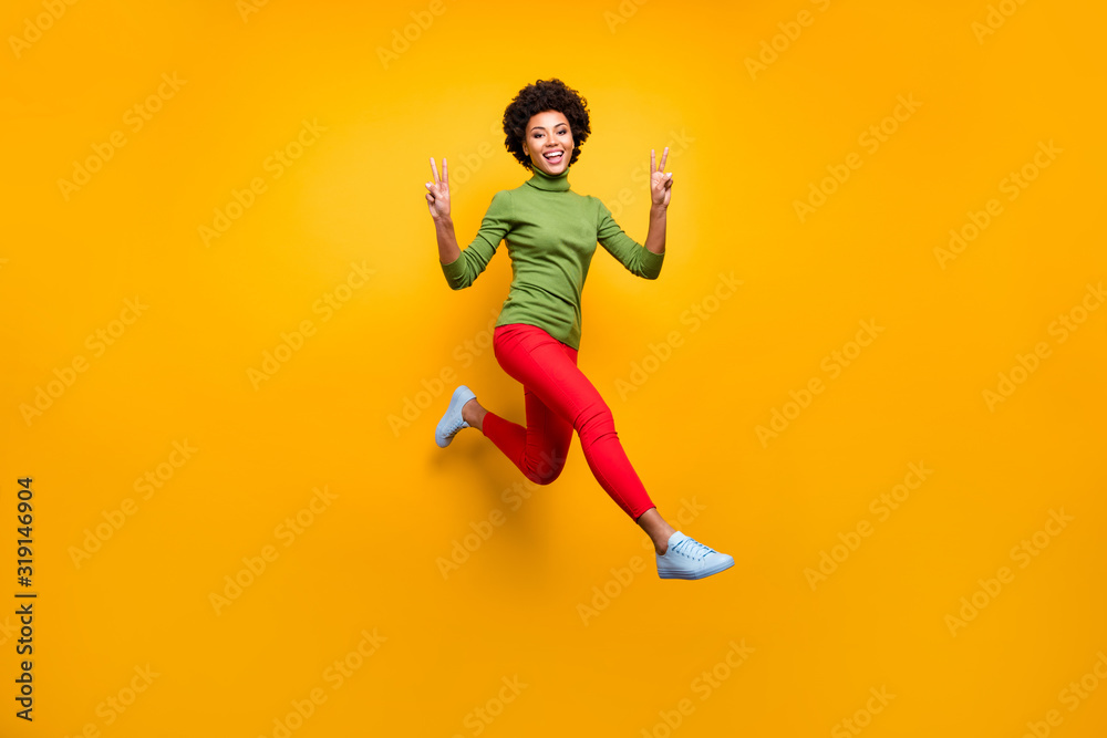 Full length body size view of her she nice attractive lovely cheerful cheery wavy-haired girl jumping showing v-sign having fun isolated over bright vivid shine vibrant yellow color background