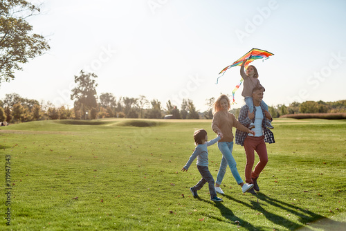 Children make life important. Happy family playing a kite. Outdoor family weekend