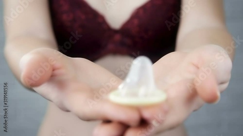 Girl in a bra gives a condom into the camera.Attractive, naked, girl, in a bra.