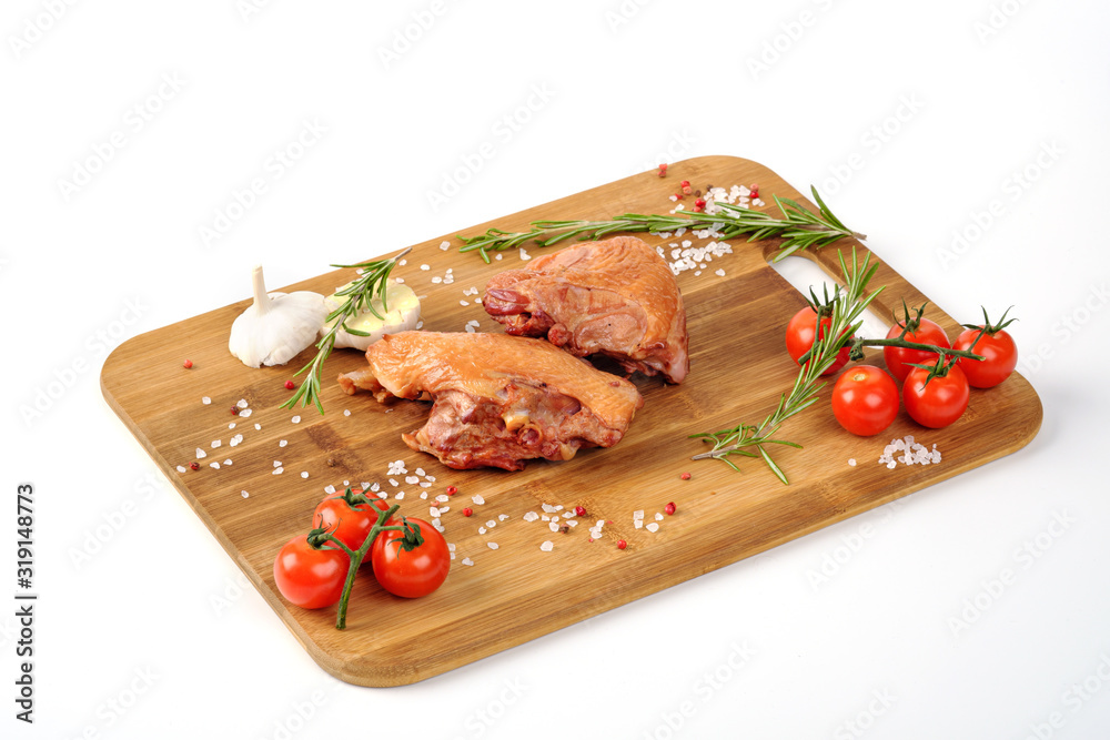 Cooked smoked meat lies on a cutting wooden board on a white background. Decorated with herbs and vegetables. Cooked smoked meat lies on a cutting wooden board on a white background. Decorated with herbs and vegetables.