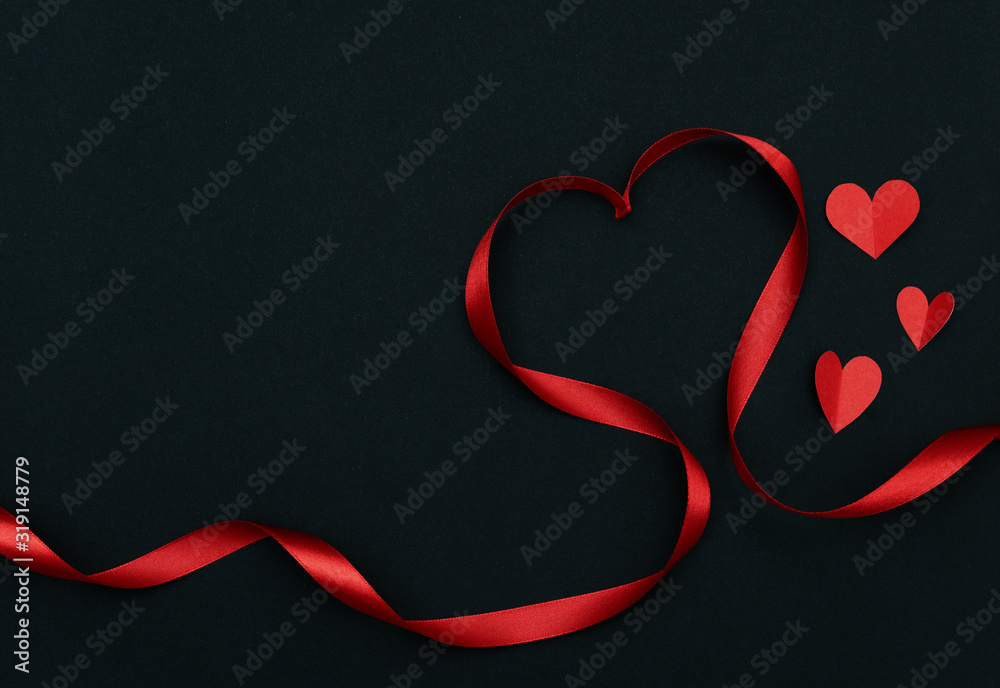 Valentine day with red heart ribbon and hearts paper on black background with space for your text.
