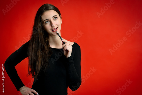 Photo of a pretty young brunette woman with a smile with good makeup on a red background. Concept girl talking in front of the camera with emotions.