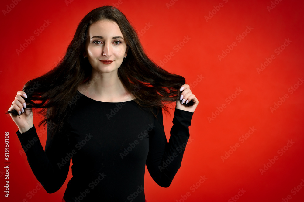Naklejka premium Photo of a pretty young brunette woman with a smile with good makeup on a red background. Concept girl talking in front of the camera with emotions.