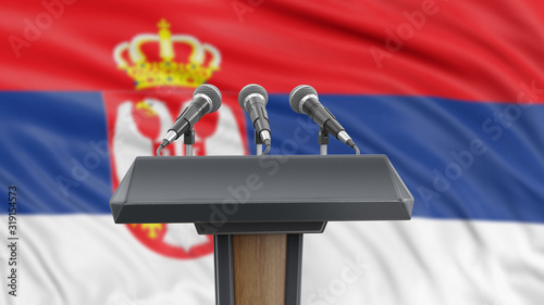 Foto Podium lectern with microphones and Serbian flag in background