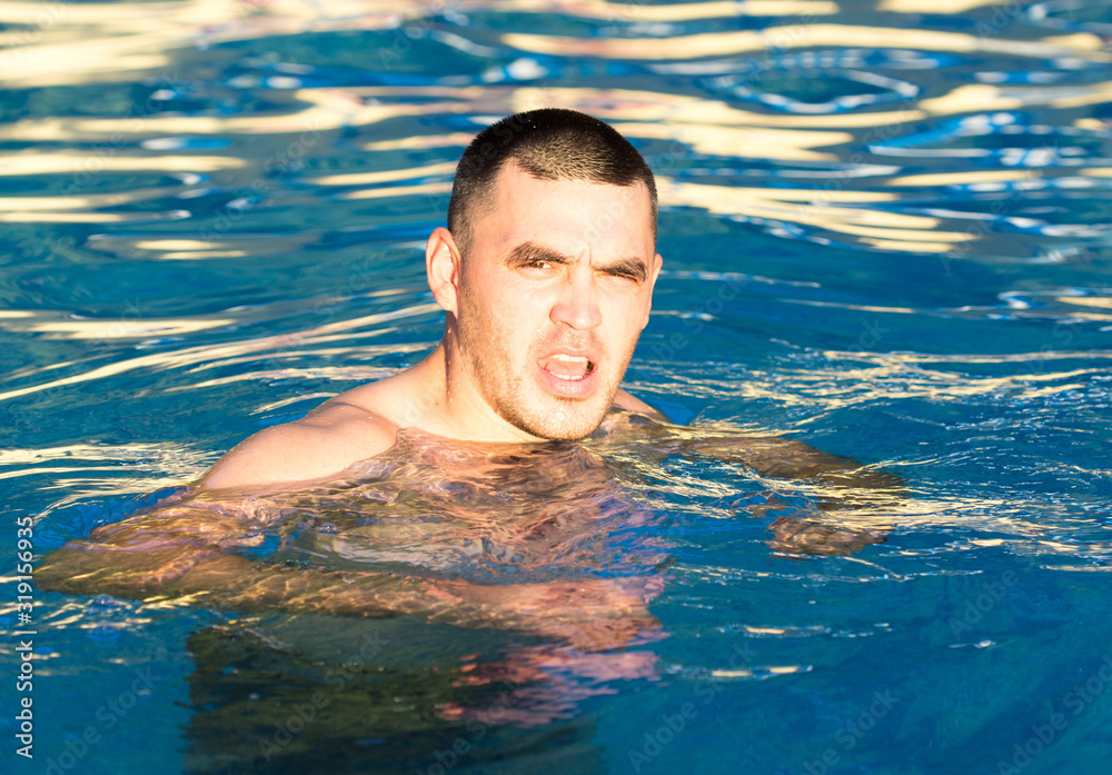 Young wet sexy muscular man posing in the swimming pool Young wet sexy muscular man posing in the swimming pool