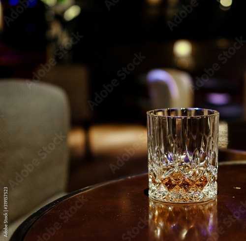 Crystal whisky glass on round wooden table in luxury lounge photo