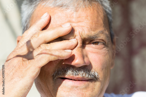 a man aged, with a hand shuts his eyes from the sun