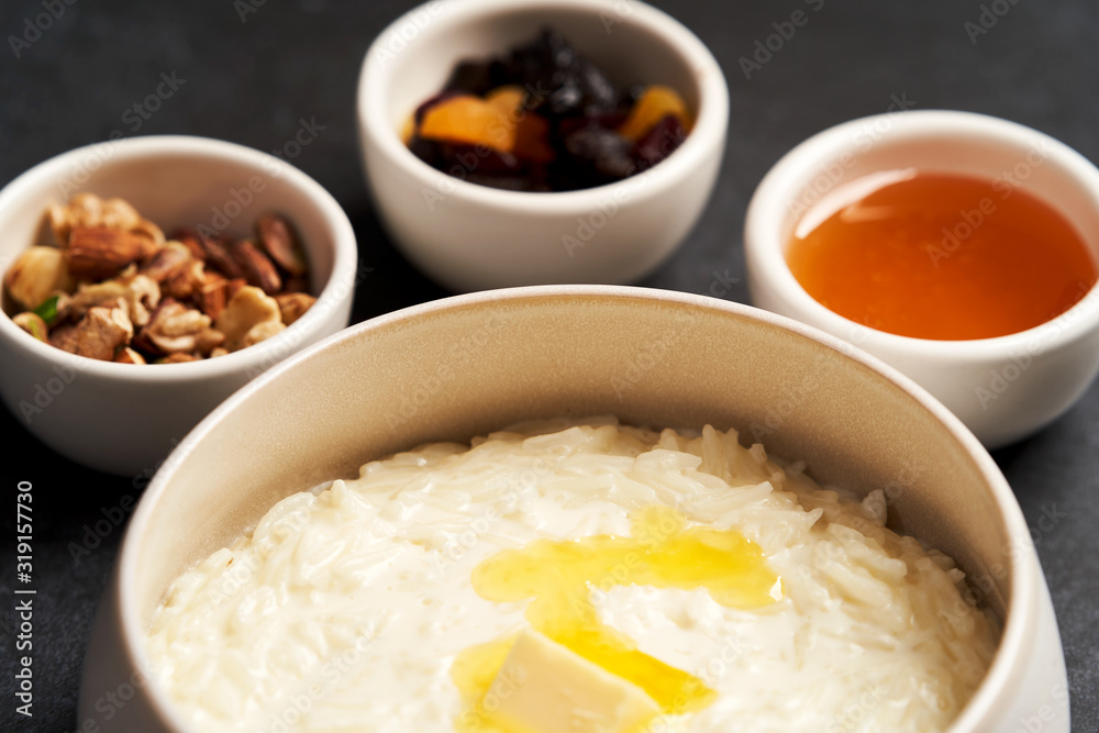 Rice porridge with milk, raisins, honey and nuts in a bowl. Rice porridge with milk, raisins, honey and nuts in a bowl.