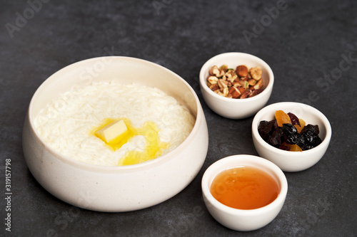 Rice porridge with milk, raisins, honey and nuts in a bowl.