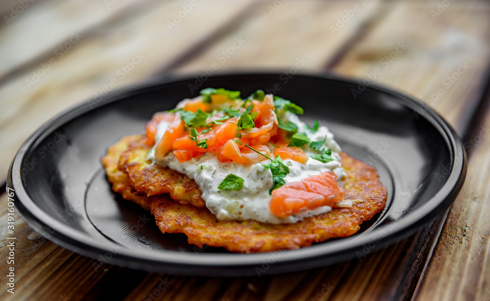 potato pancakes withsalmon fish and sour cream in a plate on wooden table potato pancakes withsalmon fish and sour cream in a plate on wooden table