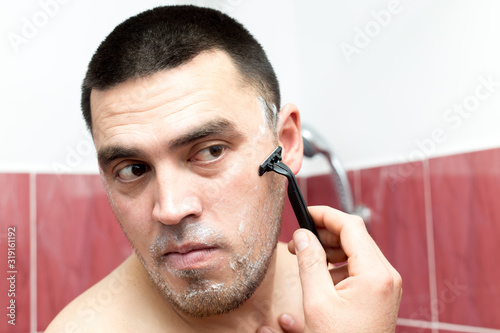 man shaves his beard in a bath