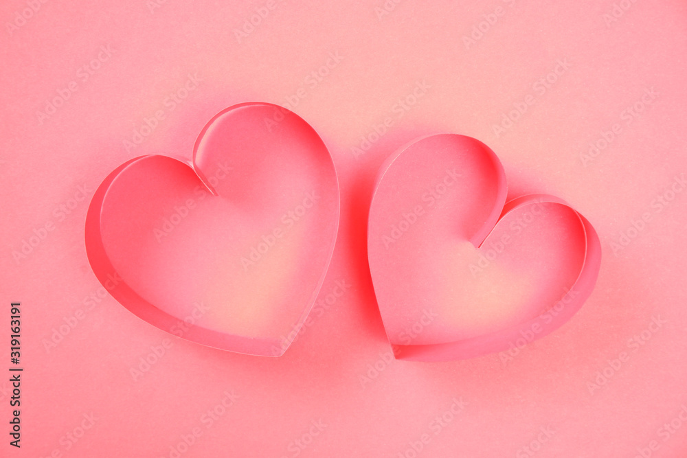 Couple of pink paper hearts on pink background top view