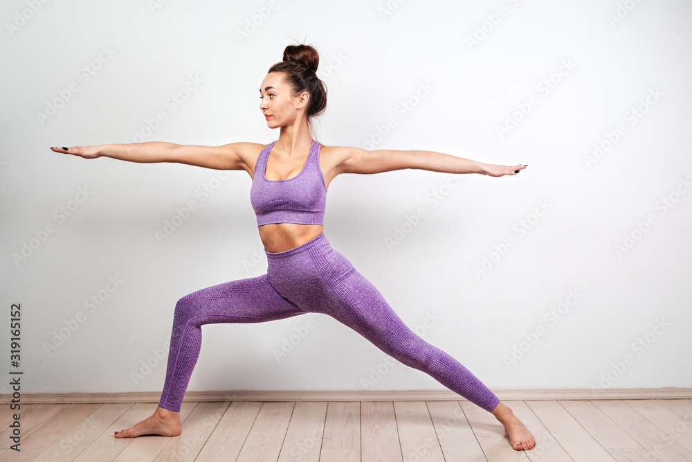 Yoga and sports concept. A young Caucasian woman is engaged in yoga, performing the pose of a warrior. White background in the background. Copy Yoga and sports concept. A young Caucasian woman is engaged in yoga, performing the pose of a warrior. White background in the background. Copy